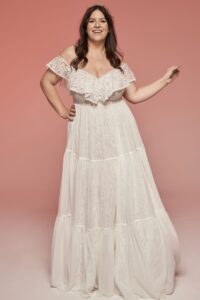 suknia ślubna w kolorze białym, z odkrytymi ramionami i falbanami.