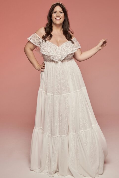 suknia ślubna w kolorze białym, z odkrytymi ramionami i falbanami.