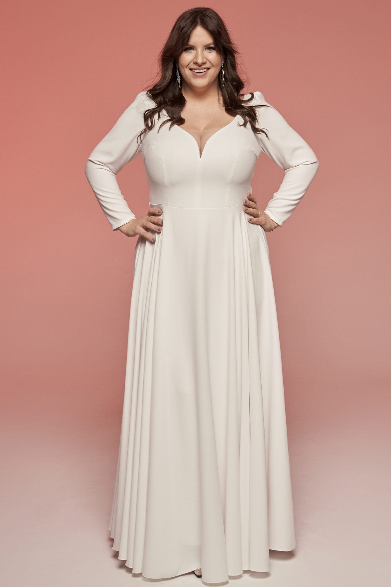 Suknia ślubna z długim rękawem i dekoltem w kształcie litery V w kolorze białym.