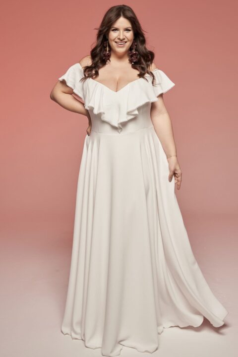 Suknia w kolorze białym z falbanami na dekolcie i długim, luźnym dołem.