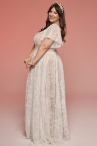 suknia ślubna z koronkowym wzorem, długimi rękawami i falbanami, w kolorze białym