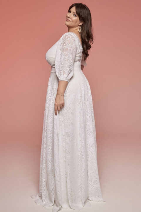 suknia ślubna z długim rękawem i koronkowym wykończeniem, na tle różowego tła