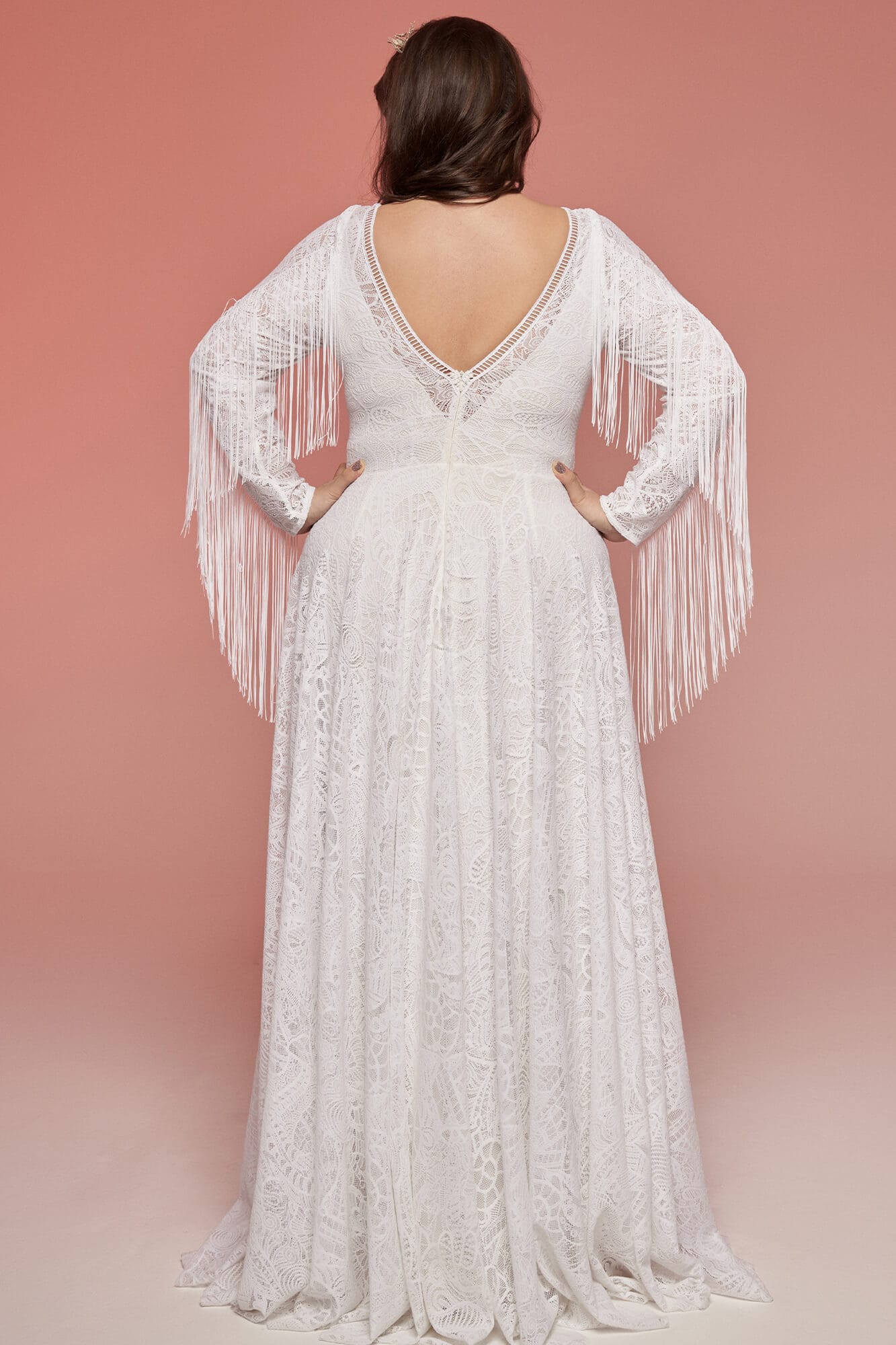 suknia ślubna z długimi rękawami i plecami w kształcie litery V, zdobiona frędzlami.