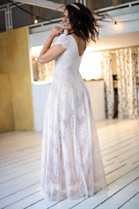 suknia ślubna z koronkowymi detalami, widok z tyłu, na tle jasnego wnętrza