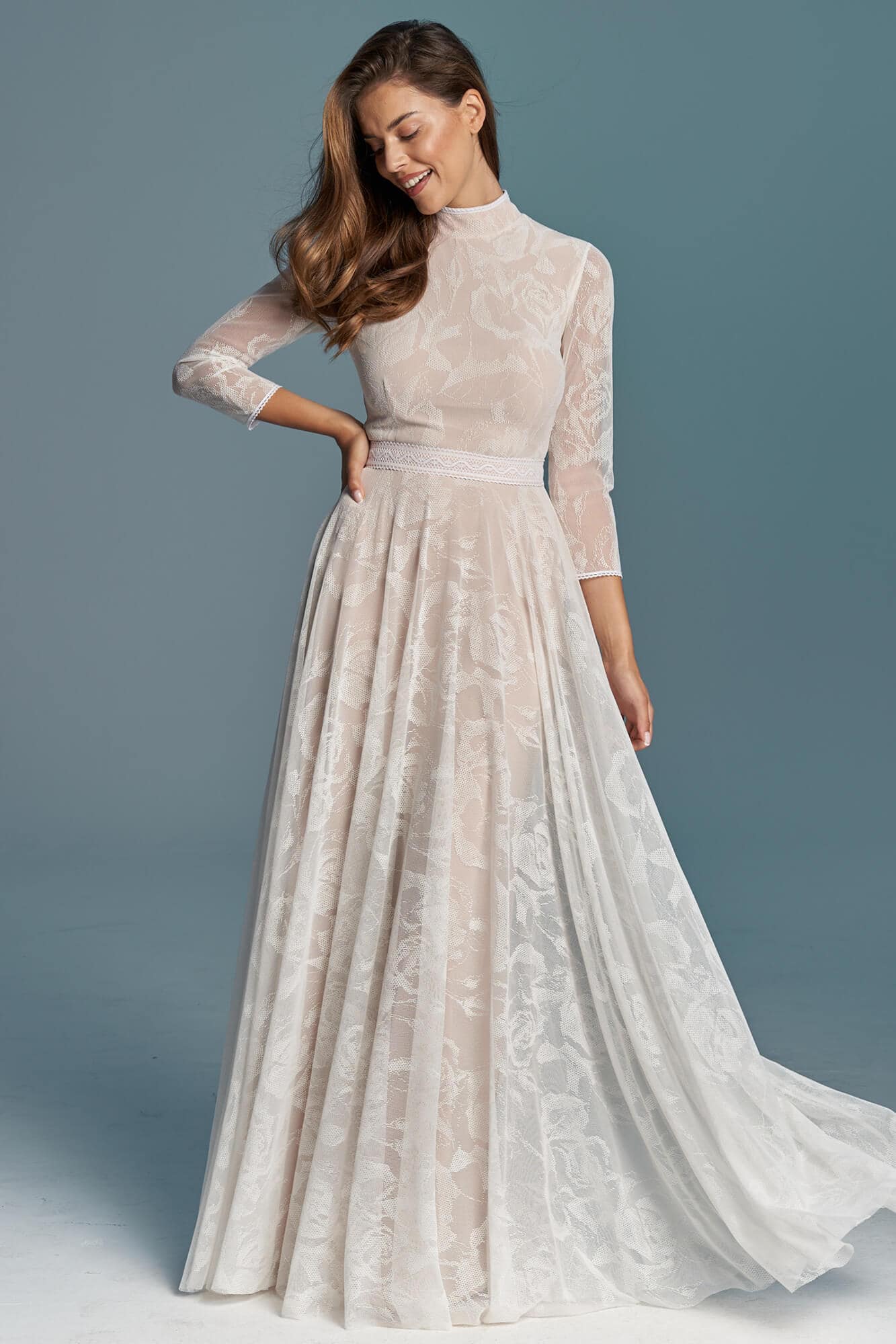 suknia ślubna z długimi rękawami i koronkowym wzorem, z długim trenem i dopasowanym fasonem.