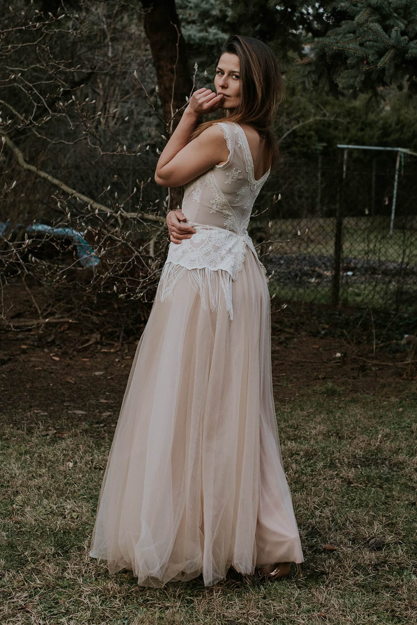 suknia ślubna z koronkowym pasem i długim, półprzezroczystym dołem w plenerze