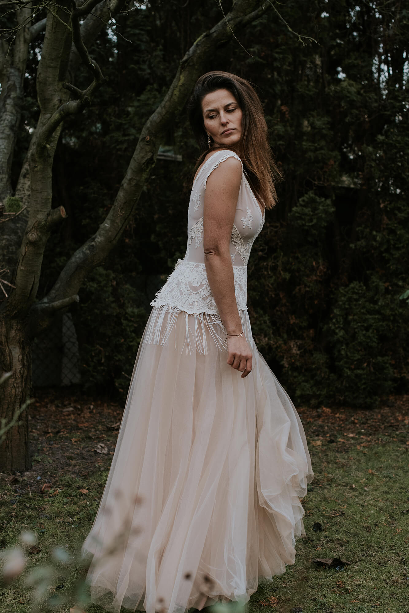 suknia ślubna z koronkowym górnym elementem i zwiewnym dołem, modelka w ogrodzie