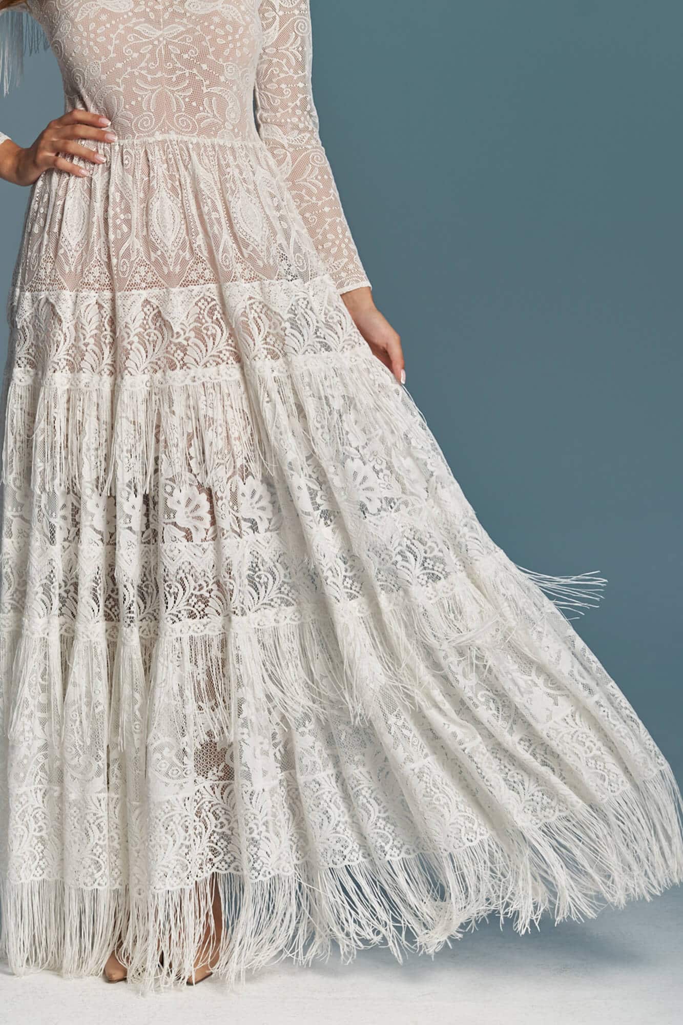 suknia ślubna z długim rękawem, koronkowym wykończeniem i frędzlami na dolnej części.