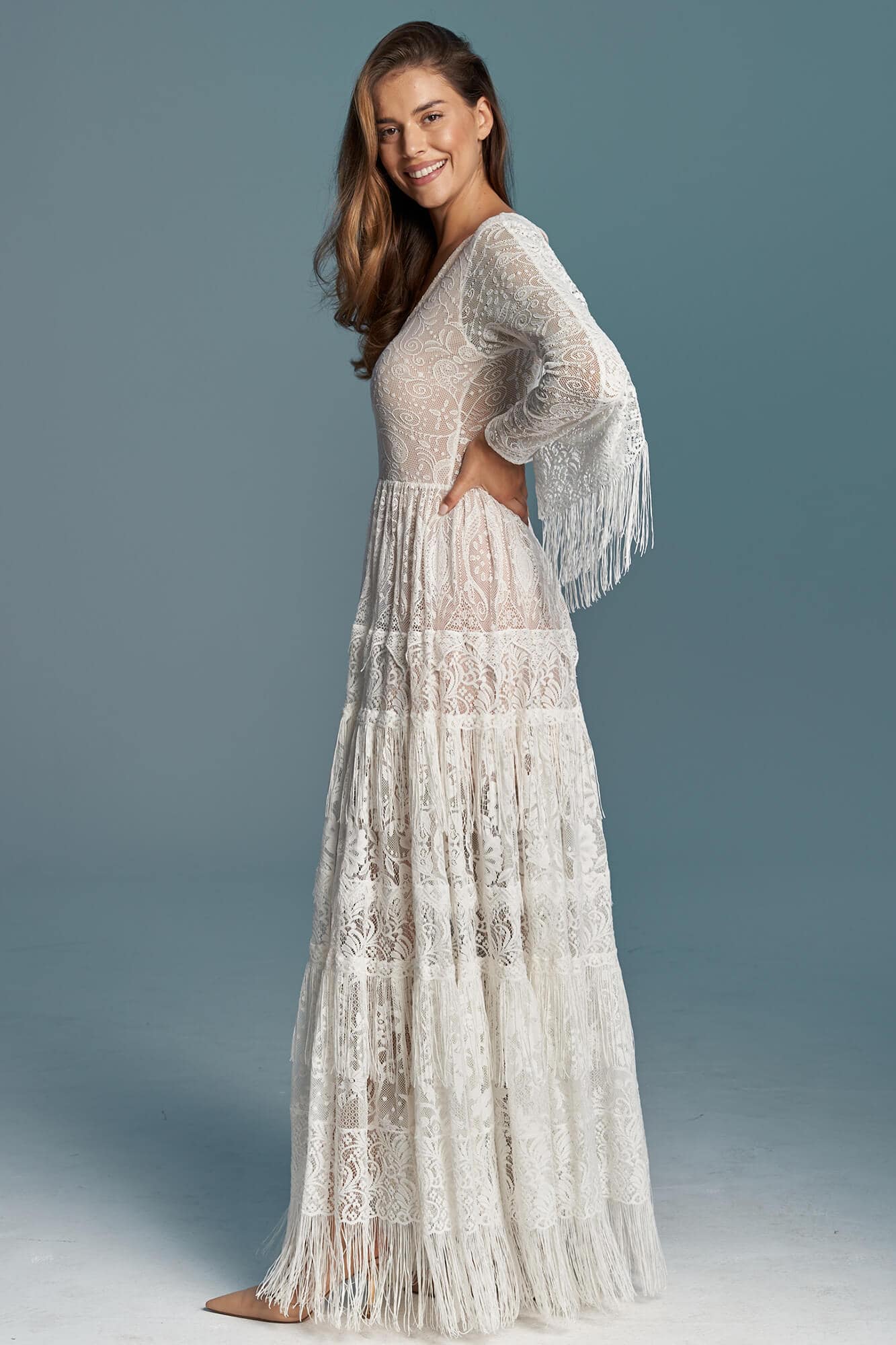 suknia ślubna z długimi rękawami, wykonana z koronkowego materiału, z falbanami u dołu.