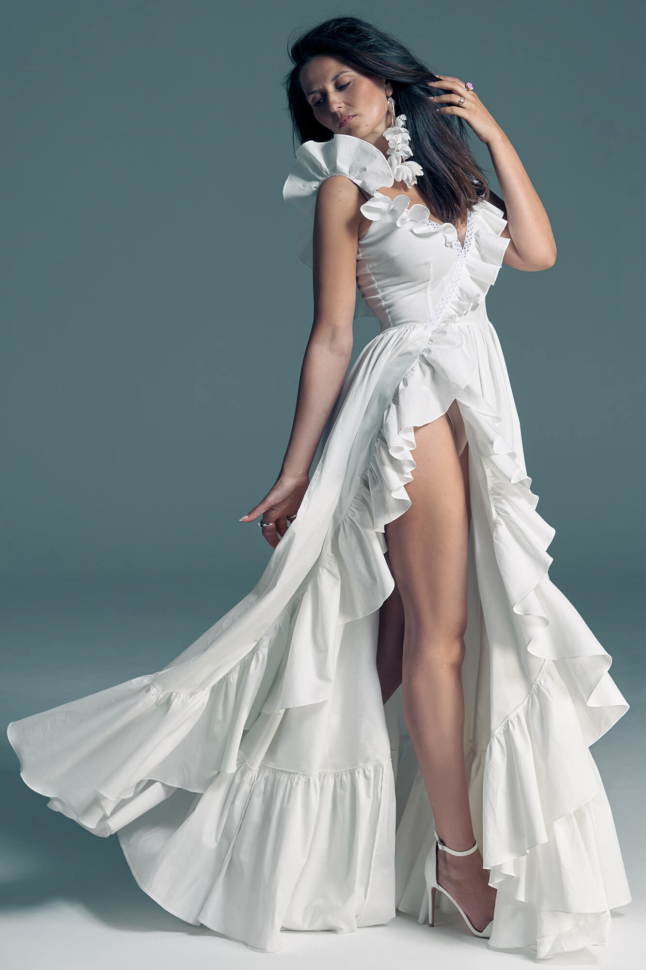 Suknia ślubna z falbaniastymi rękawami i rozcięciem z przodu.