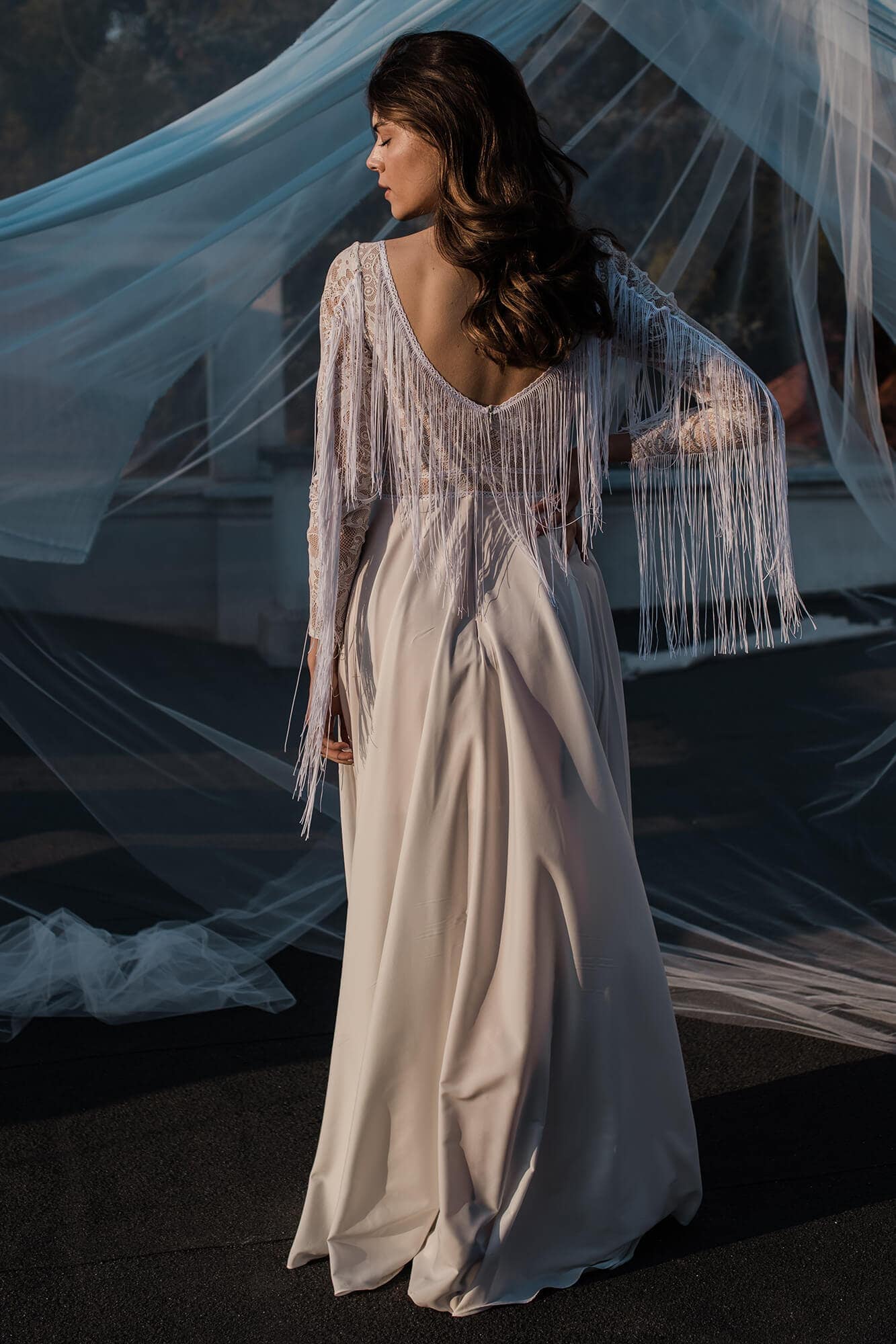 suknia ślubna z długimi rękawami i frędzlami, widok z tyłu na osobę w białej sukni