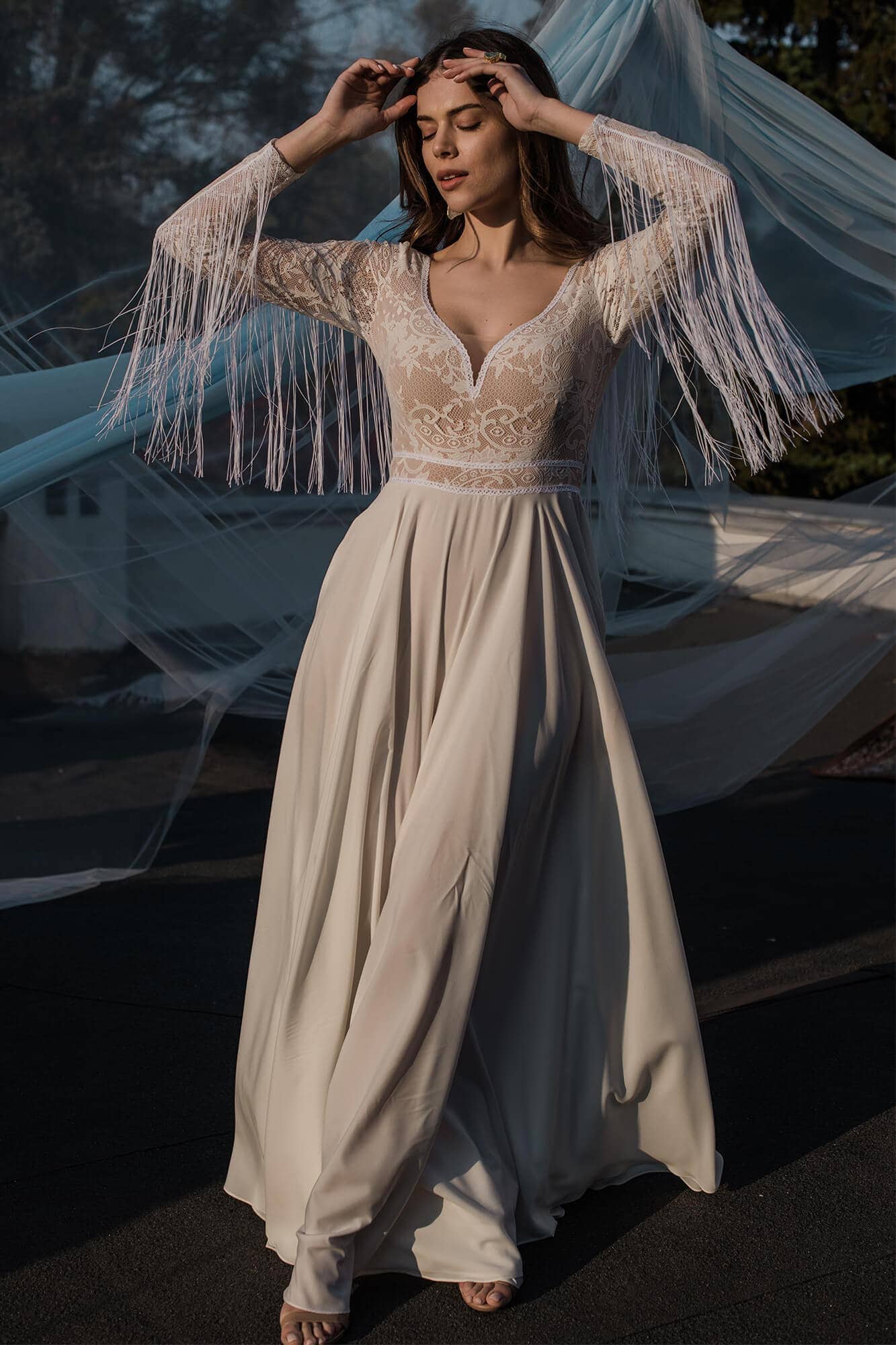 suknia ślubna z długimi rękawami i frędzlami, o rozkloszowanej dolnej części.