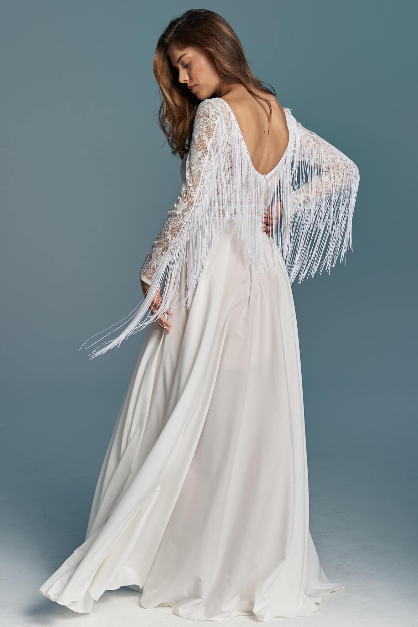 suknia ślubna z długimi rękawami i frędzlami, widok z tyłu na tle szarym