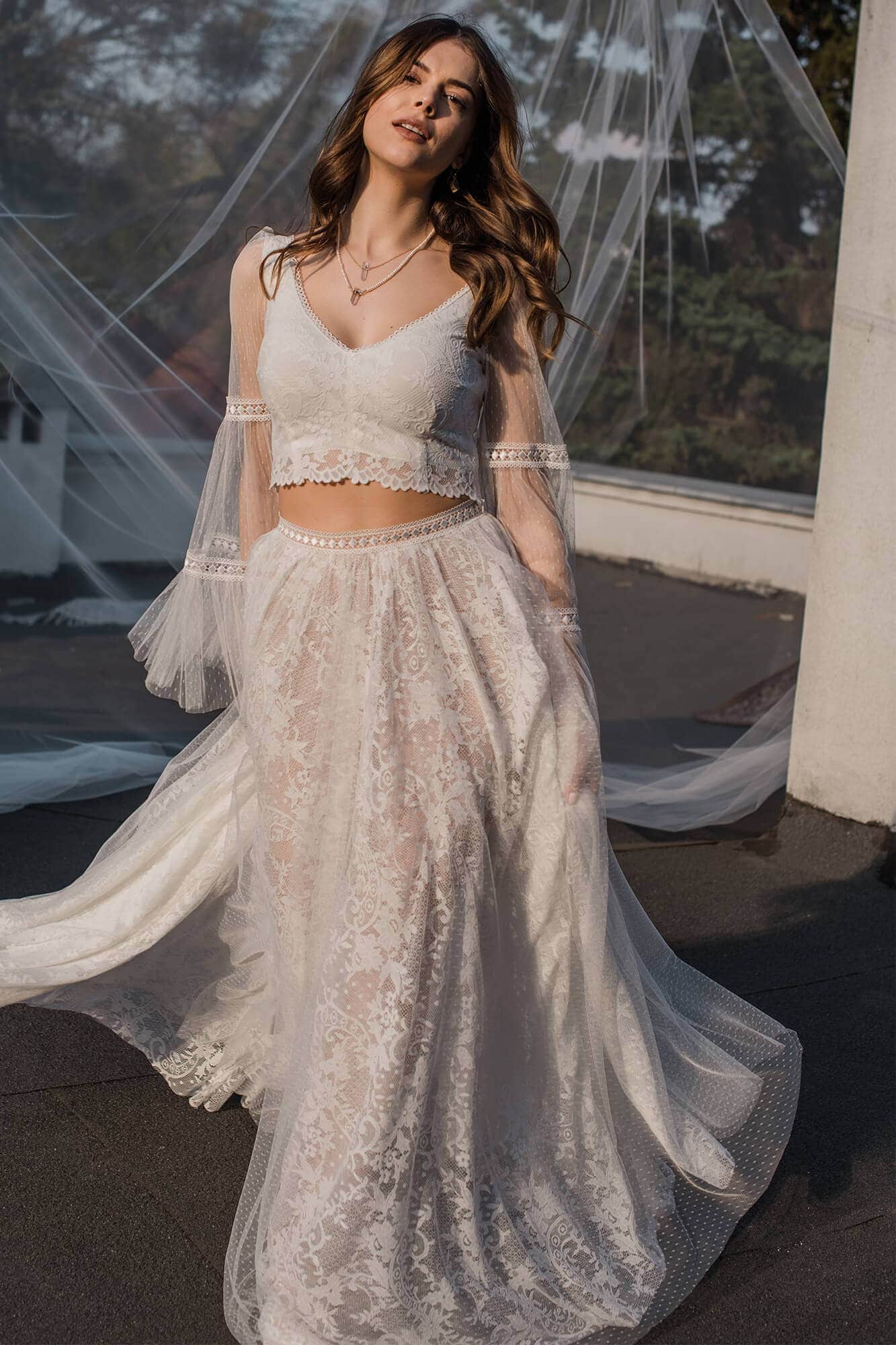 suknia ślubna z koronkowym dołem i górą z dekoltem w serek, modelka w jasnym otoczeniu
