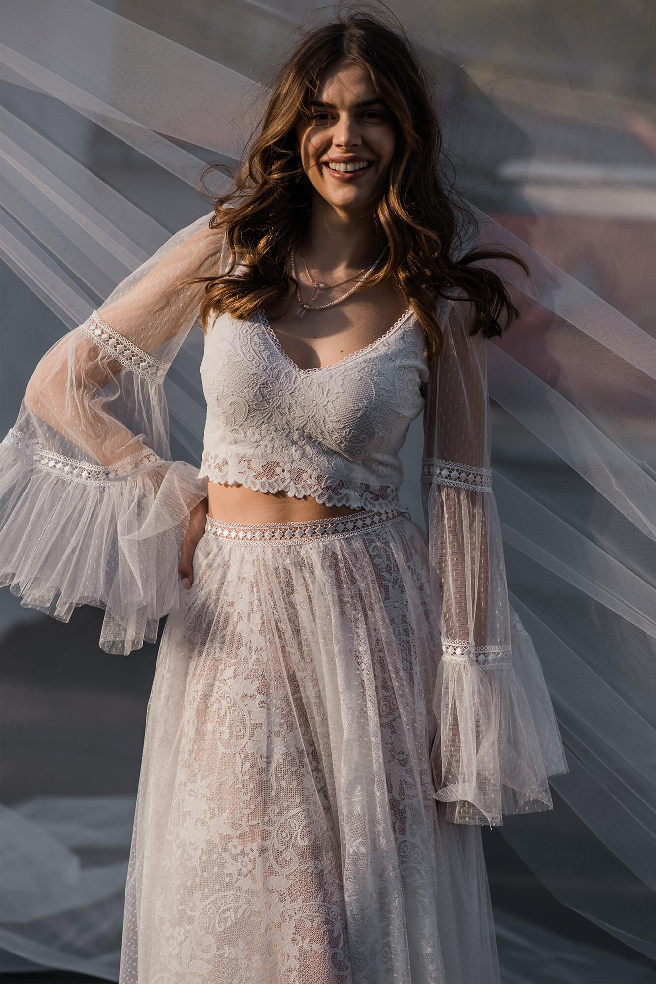 Suknia ślubna z koronkowym gorsetem i długimi, przezroczystymi rękawami.