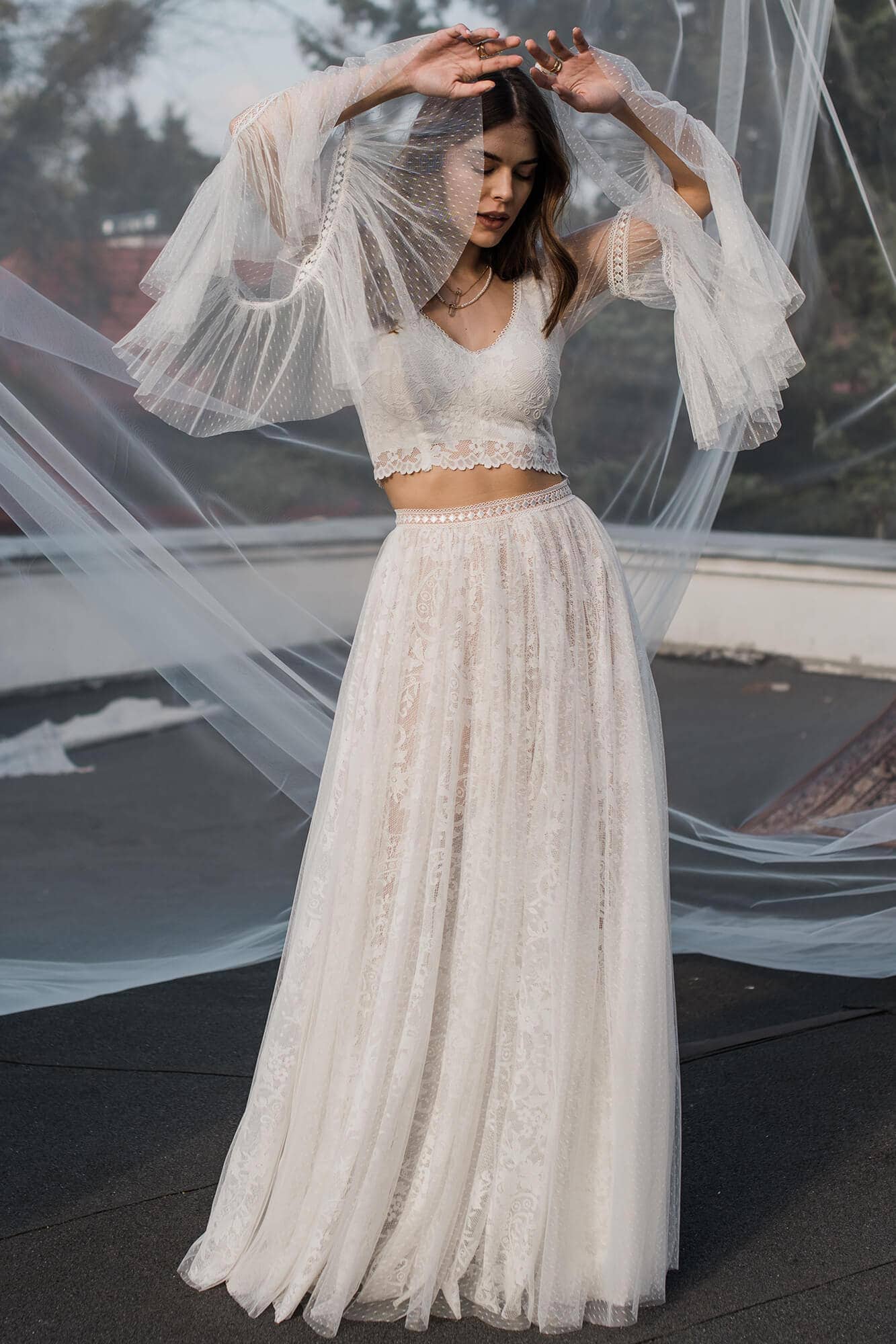 suknia ślubna z koronkowym górnym elementem i długim, zwiewnym dołem, z transparentnymi rękawami