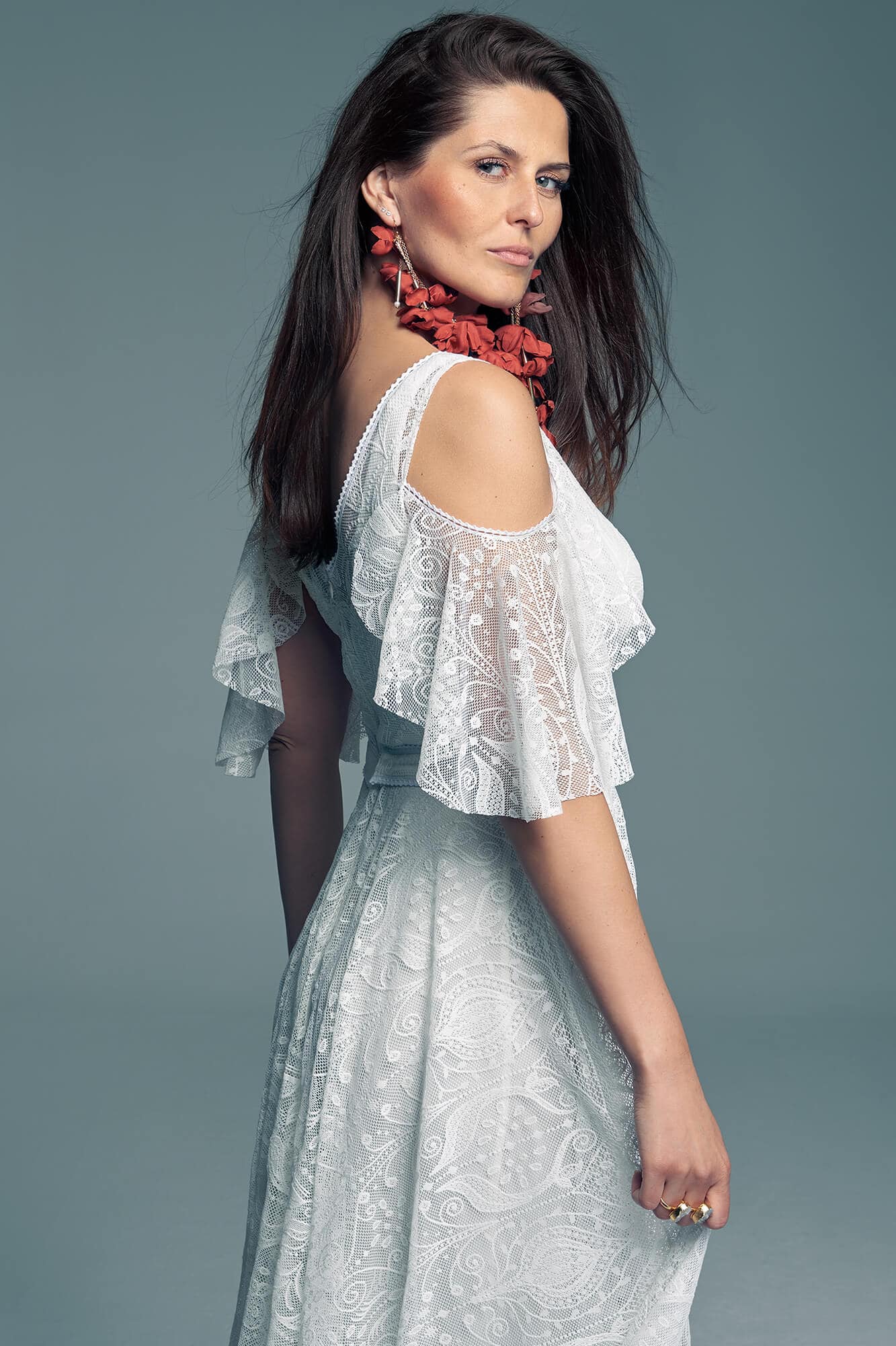 Suknia ślubna z koronkowymi rękawami i wzorem na tkaninie, prezentowana przez kobietę.