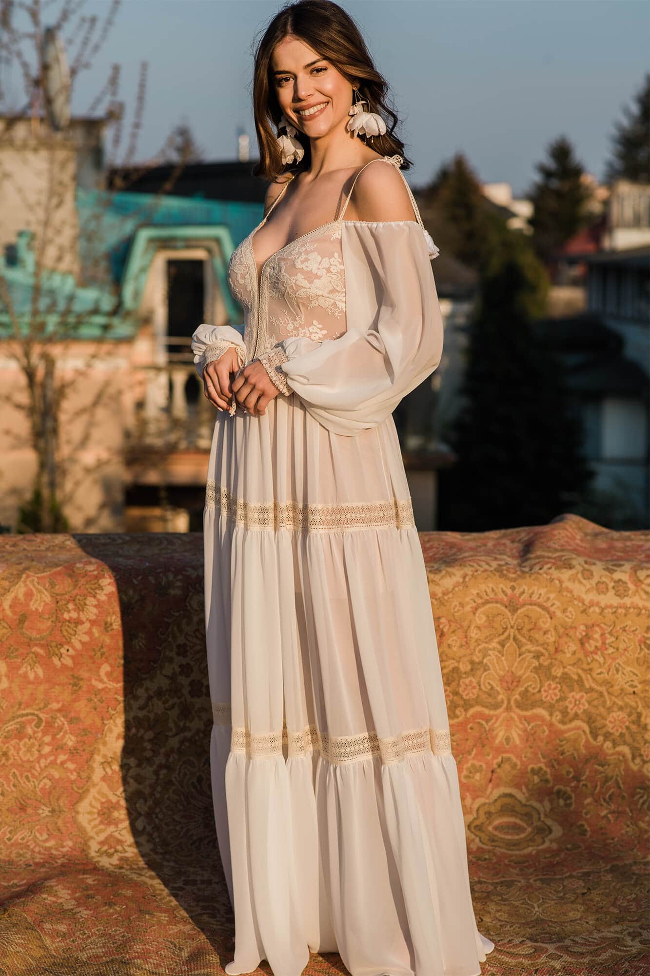 suknia w kolorze białym z długimi rękawami i zdobieniami w dolnej części.