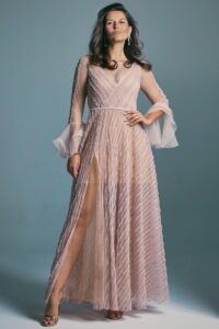 suknia w kolorze różowym z długimi rękawami i rozcięciem na nogę, z ozdobnym paskiem w talii