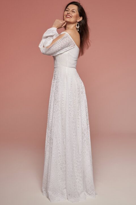 suknia ślubna z długimi rękawami, w kolorze białym, z delikatnym wzorem, prezentowana na modelce w profilu.