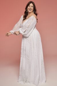 suknia ślubna z długimi rękawami i głębokim dekoltem, w kolorze białym.