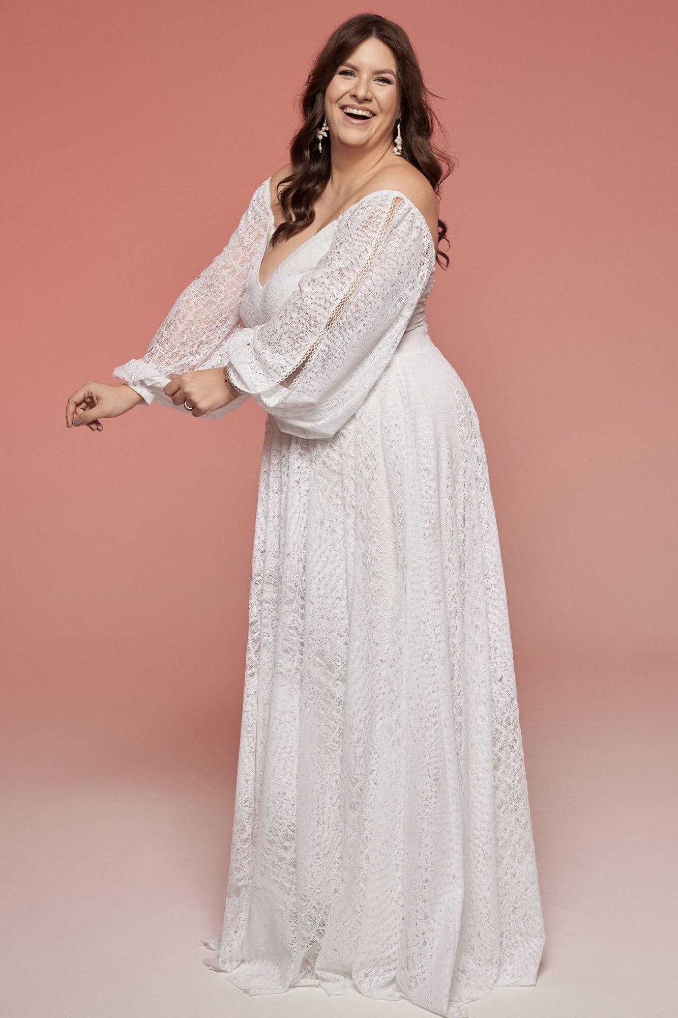 suknia ślubna z długimi rękawami i głębokim dekoltem, w kolorze białym.