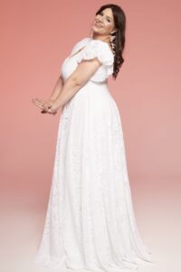 suknia ślubna z białego materiału, z falbanami na ramionach i wzorem w kwiaty