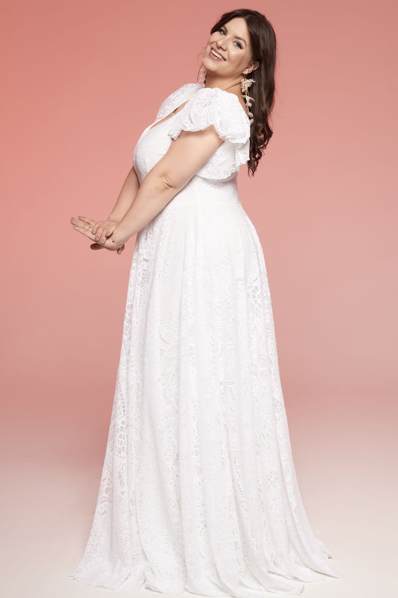 suknia ślubna z białego materiału, z falbanami na ramionach i wzorem w kwiaty