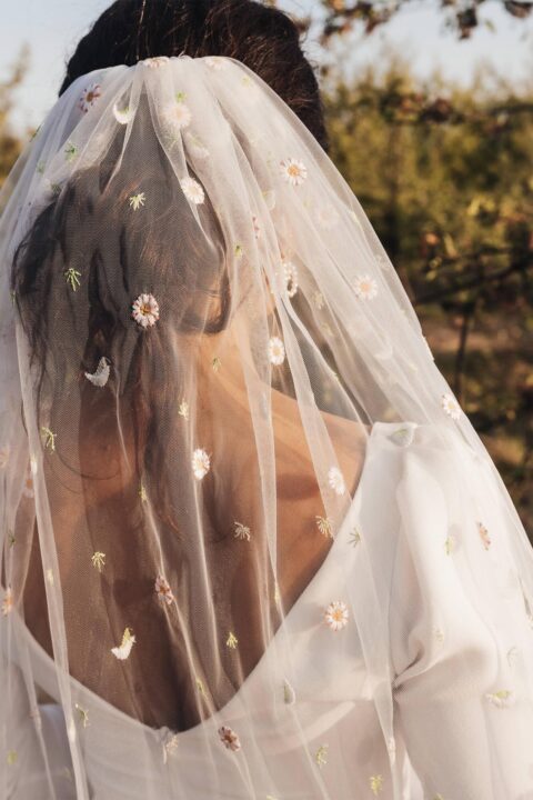 Suknia ślubna z koronkowym welonem zdobionym haftem w kształcie kwiatów.