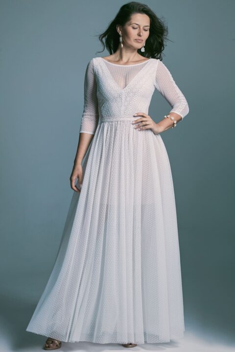 suknia ślubna z długimi rękawami i lekko przezroczystą górą, w kolorze białym.