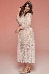 Suknia ślubna z długim rękawem, wykonana z koronkowego materiału w jasnym kolorze.