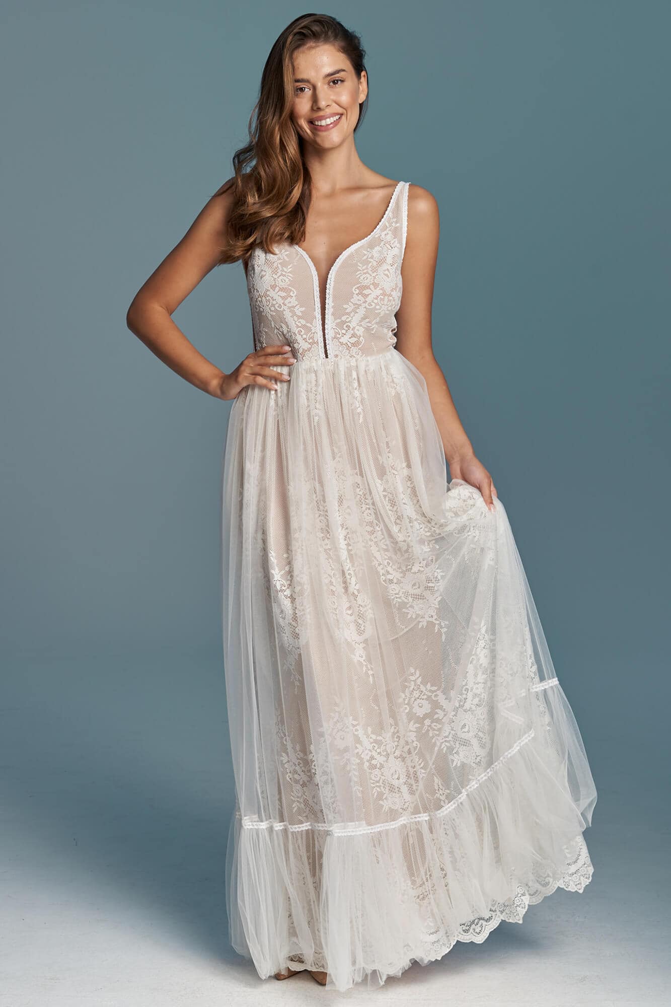 suknia ślubna z koronkowym gorsetem i tiulowym dołem, modelka trzyma materiał w dłoni