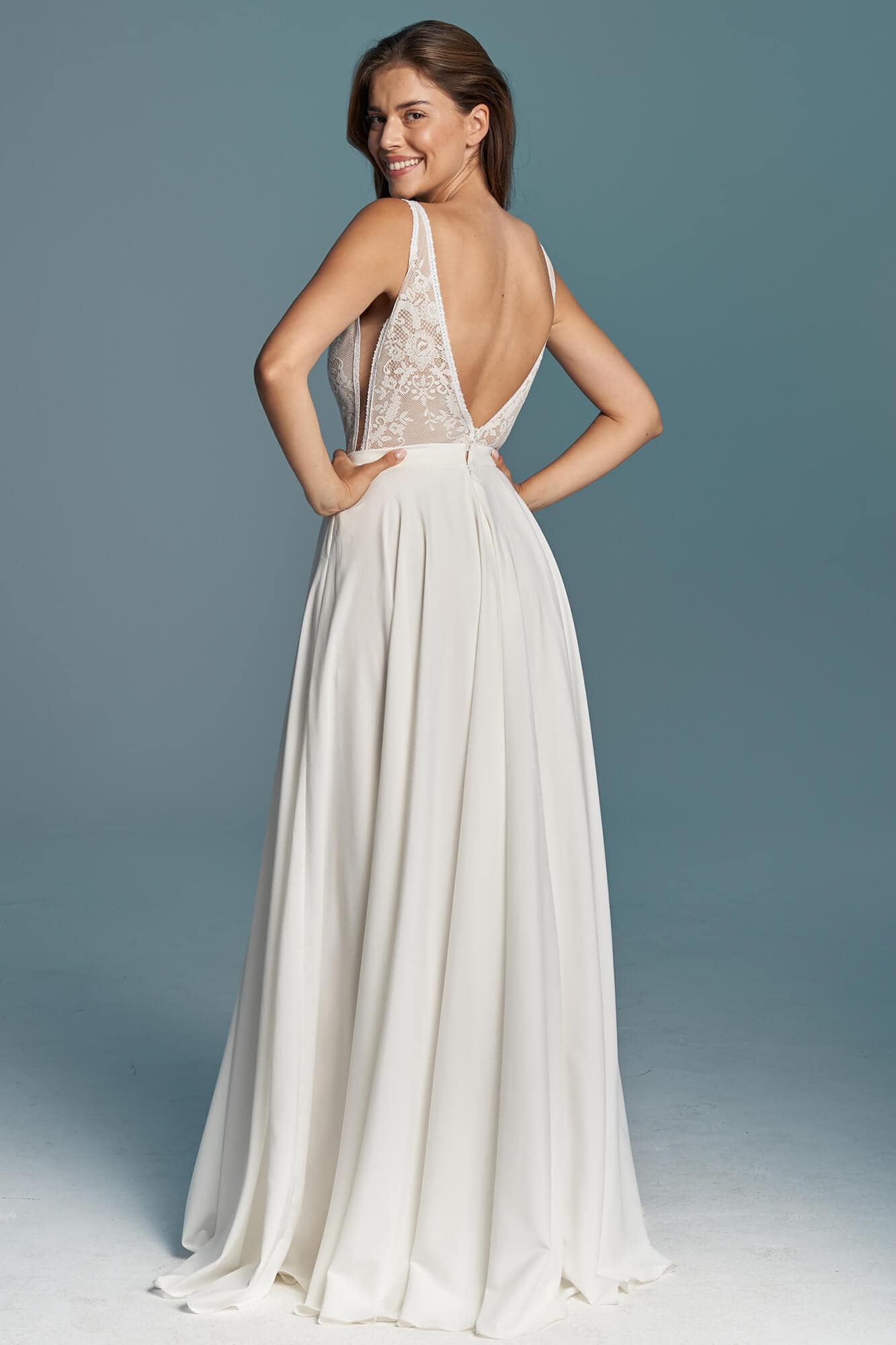 suknia ślubna z odkrytymi plecami i delikatnymi ramiączkami, w kolorze białym.