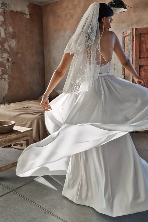 suknia ślubna z dekoltem i koronkowymi detalami, obracająca się na tle rustykalnego wnętrza