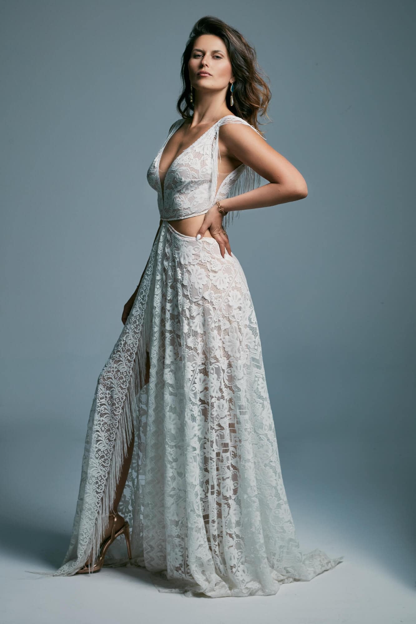 suknia ślubna z koronkowym materiałem, głębokim dekoltem i rozcięciem, modelowana na sylwetce kobiety