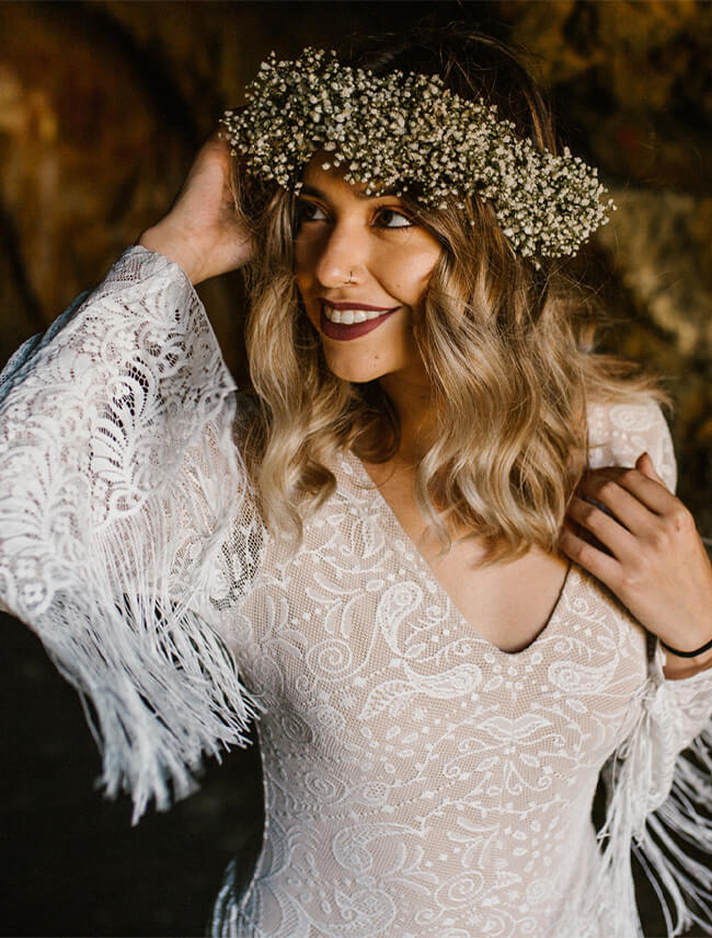 Suknia ślubna z koronkowymi rękawami i ozdobą z kwiatów na głowie.