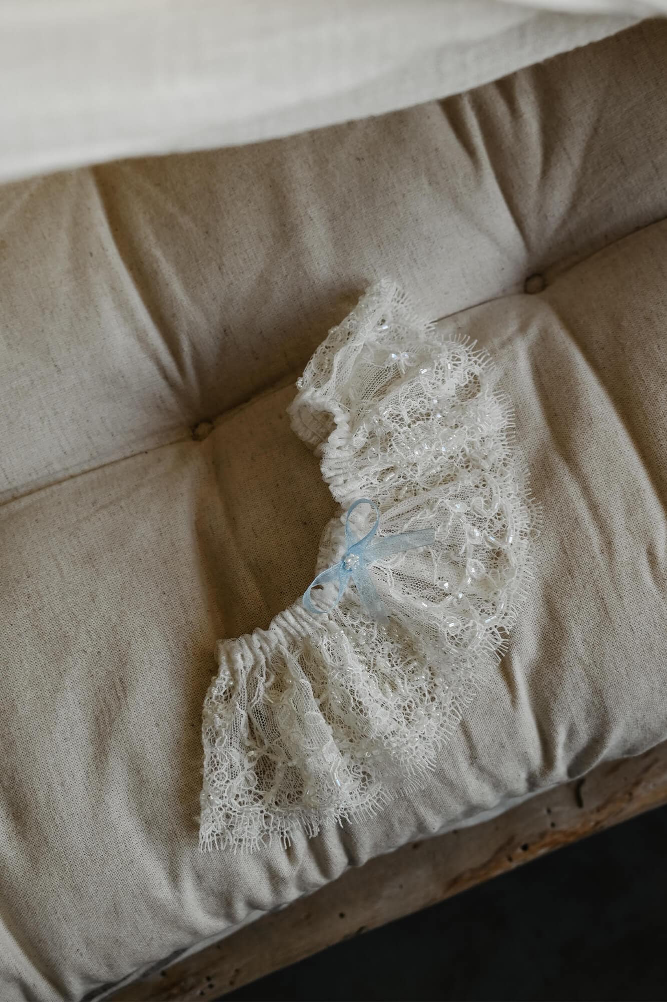 suknia ślubna z koronkowymi detalami leżąca na beżowej sofie