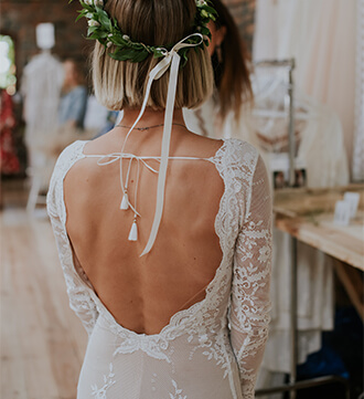 suknia ślubna z długimi rękawami i odkrytymi plecami, zdobiona koronką.