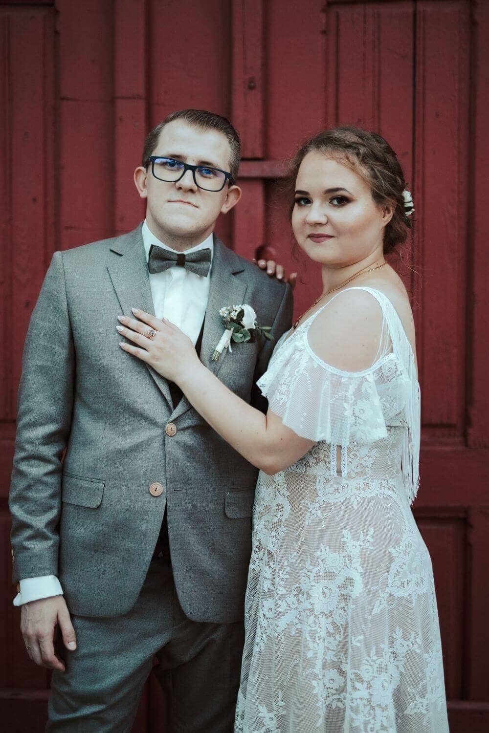 Para w strojach ślubnych, kobieta w koronkowej sukni ślubnej i mężczyzna w szarym garniturze.