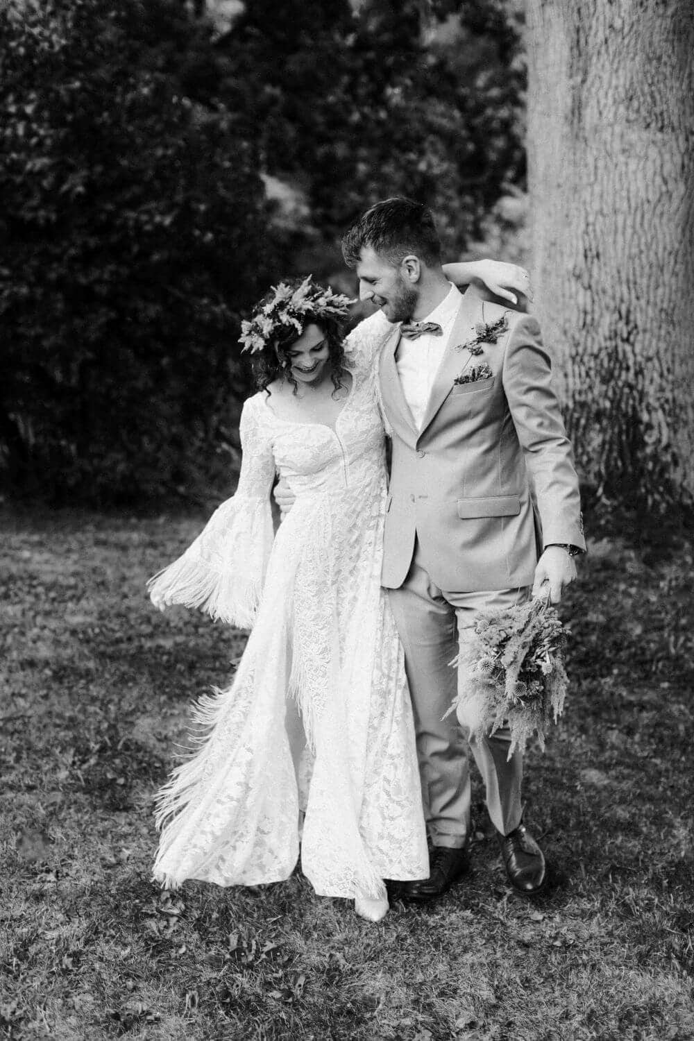 suknia ślubna z długimi rękawami, para w eleganckich strojach na tle zieleni