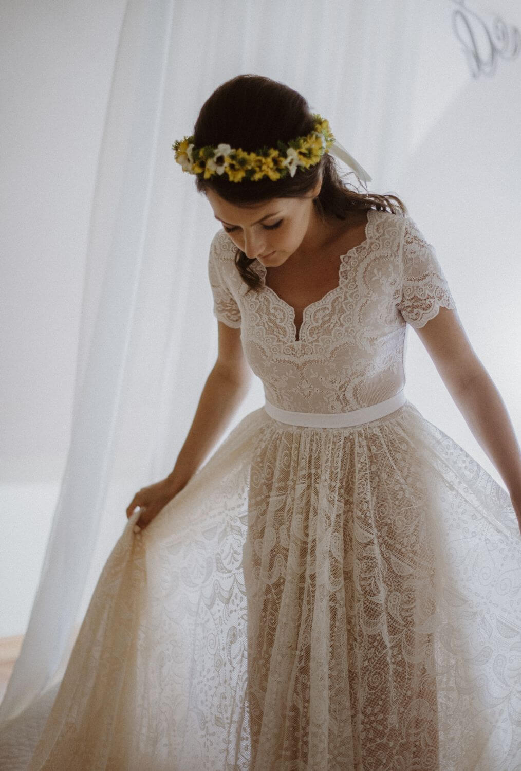 suknia ślubna z koronkowym wzorem i długim, zwiewnym dołem, z białym paskiem w talii