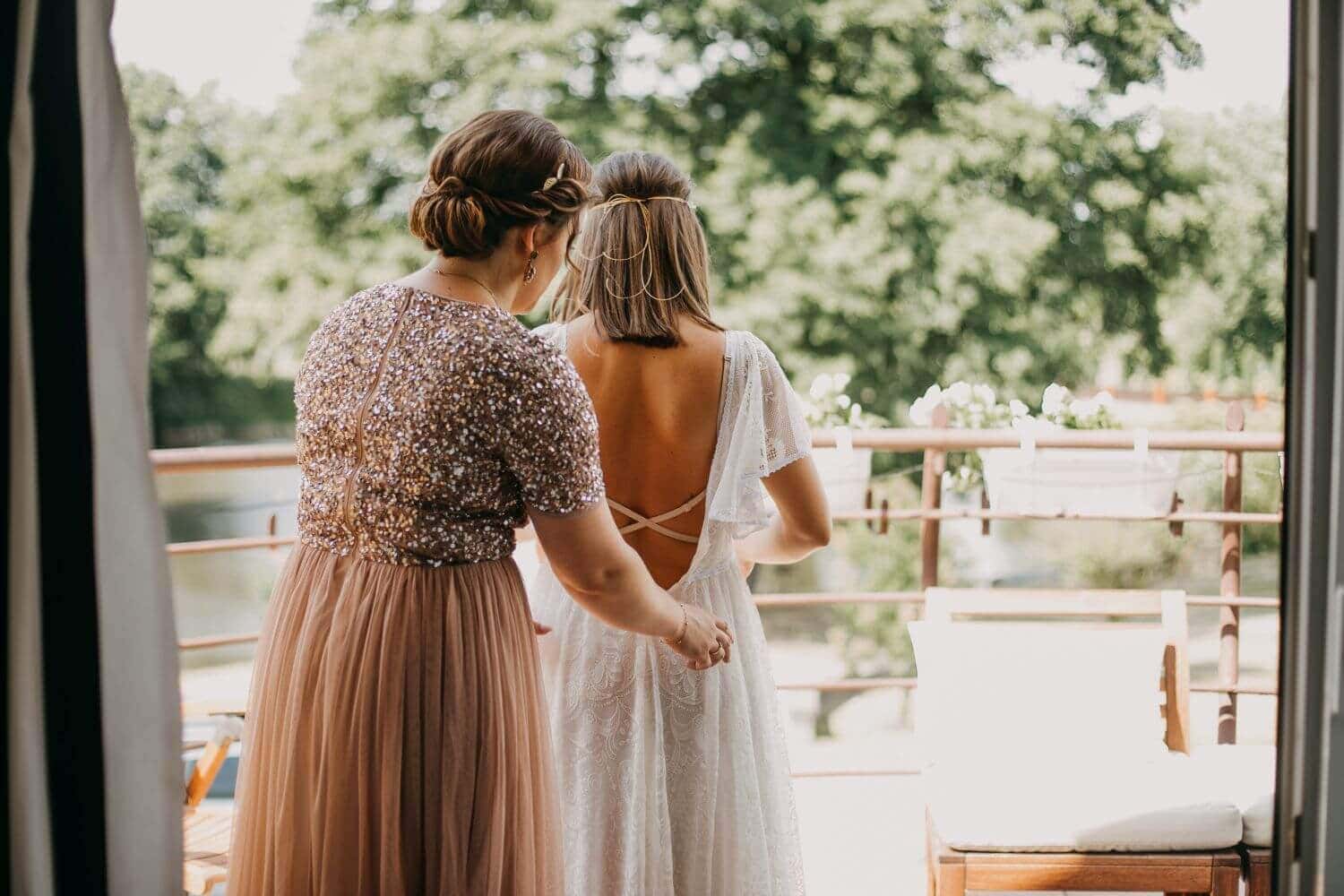 Osoba w sukni ślubnej z koronkowymi rękawami, przygotowująca się do ceremonii.