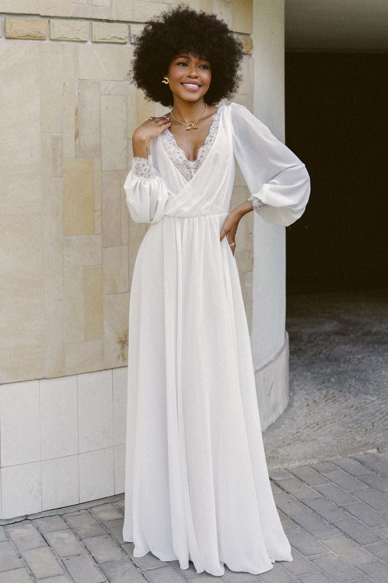 suknia ślubna z długimi rękawami, dekoltem w kształcie litery V i luźnym krojem.