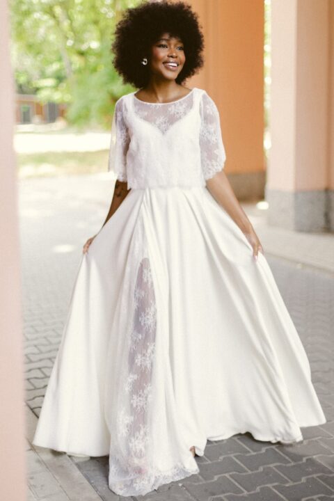 suknia ślubna z długim rękawem, w kolorze białym, z koronkowym wykończeniem na górze.