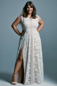 Suknia ślubna z koronkowym wykończeniem i rozcięciem na nogę, noszona przez kobietę.