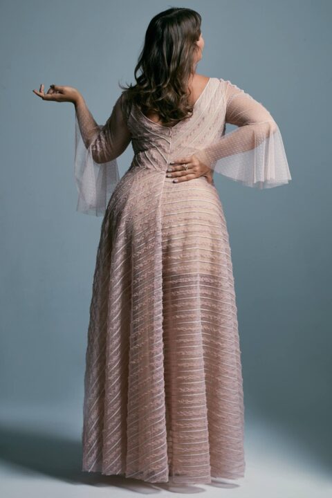 suknia ślubna w odcieniu różowym z długimi, przezroczystymi rękawami i falującą teksturą materiału