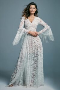 suknia ślubna z długimi rękawami, wykonana z koronkowego materiału, w kolorze białym.