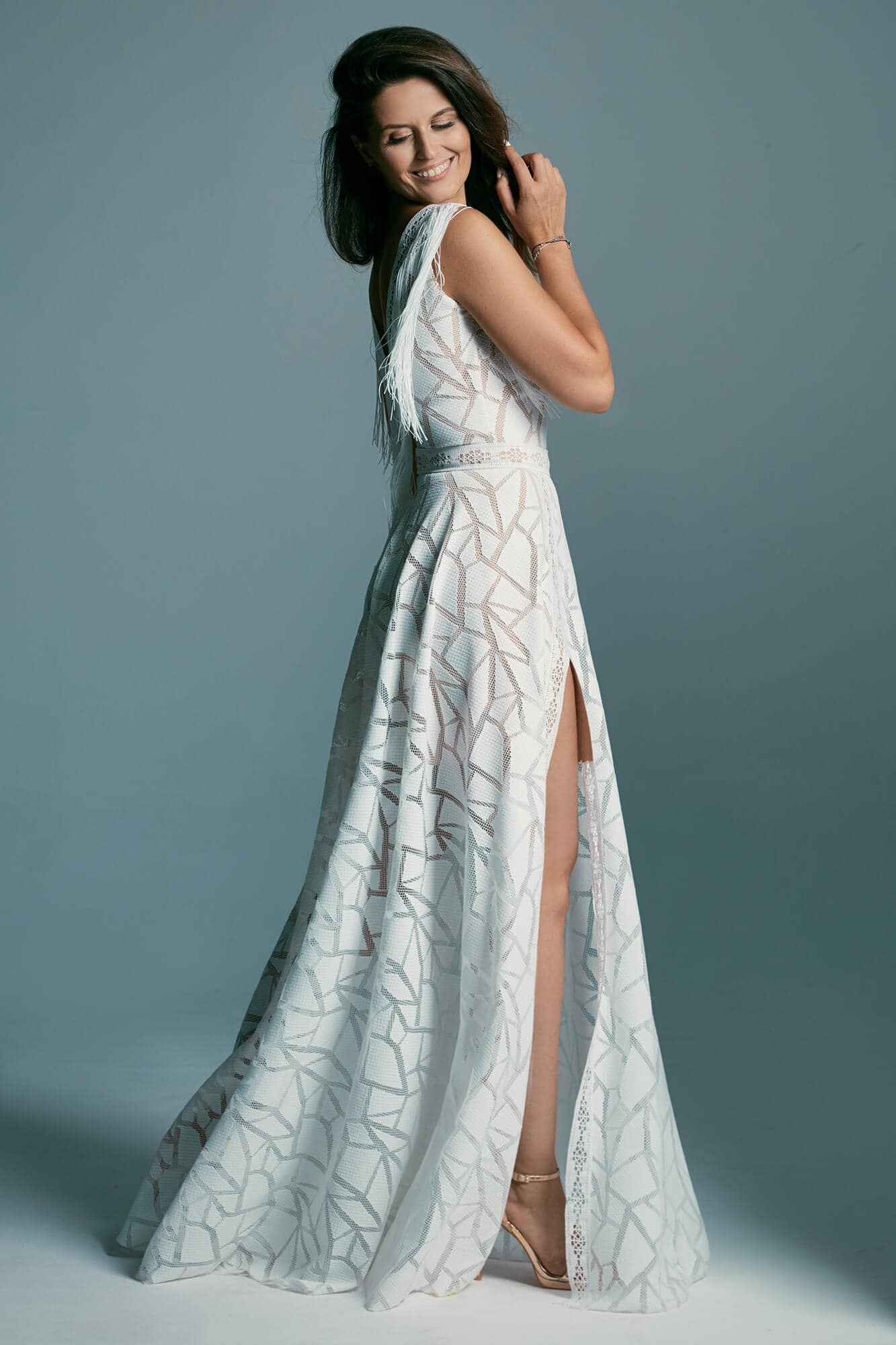 suknia ślubna z dekoltem i rozcięciem, wykonana z białego materiału z wzorem.