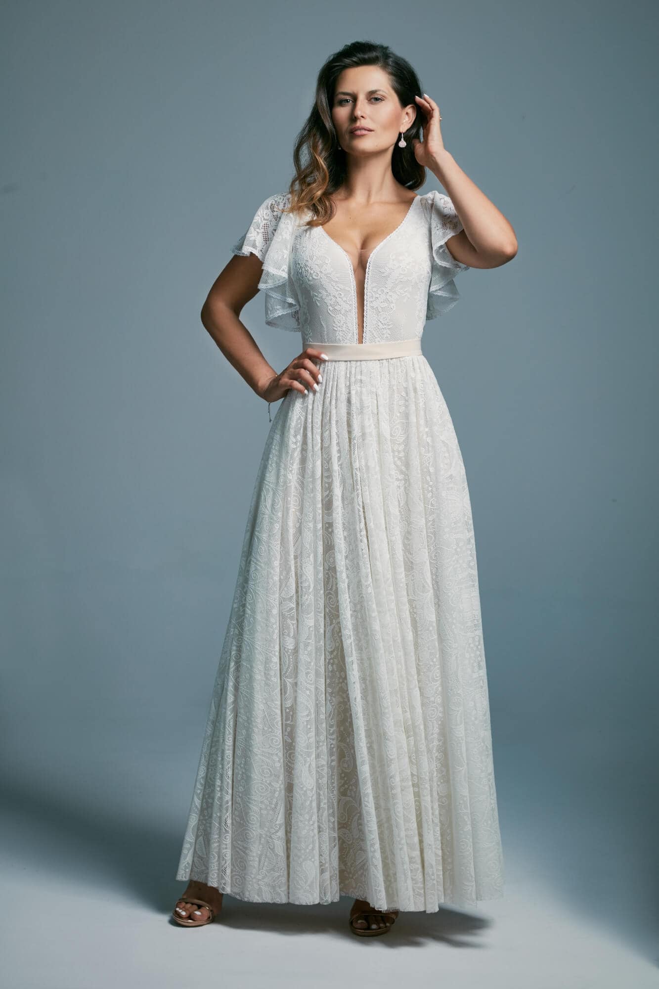 suknia ślubna z dekoltem w serek i krótkimi rękawami, wykonana z białego materiału.