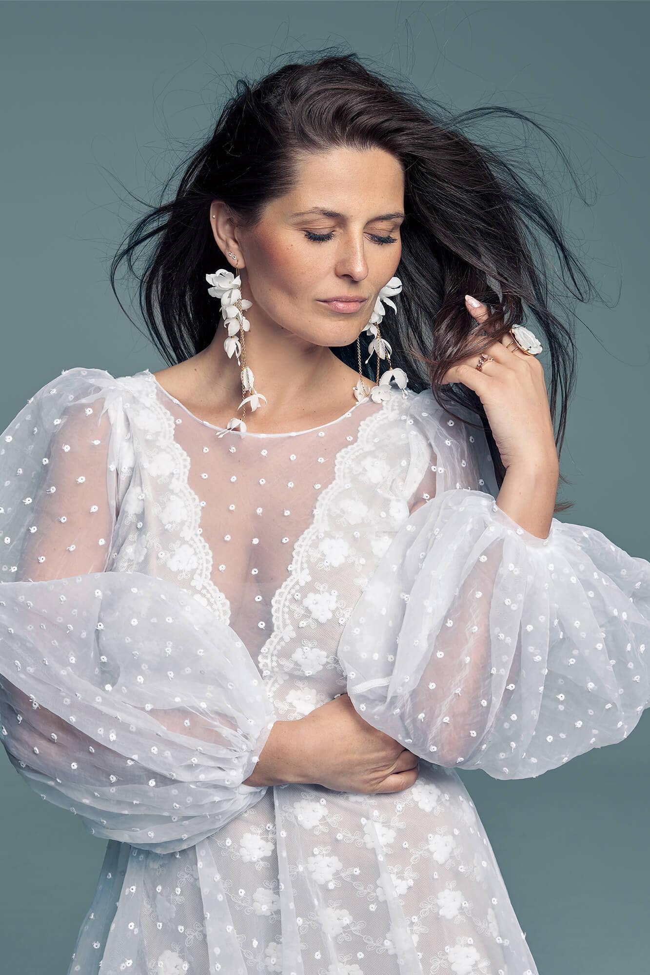 Suknia ślubna z przezroczystym górnym materiałem i szerokimi rękawami, ozdobiona koralikami.